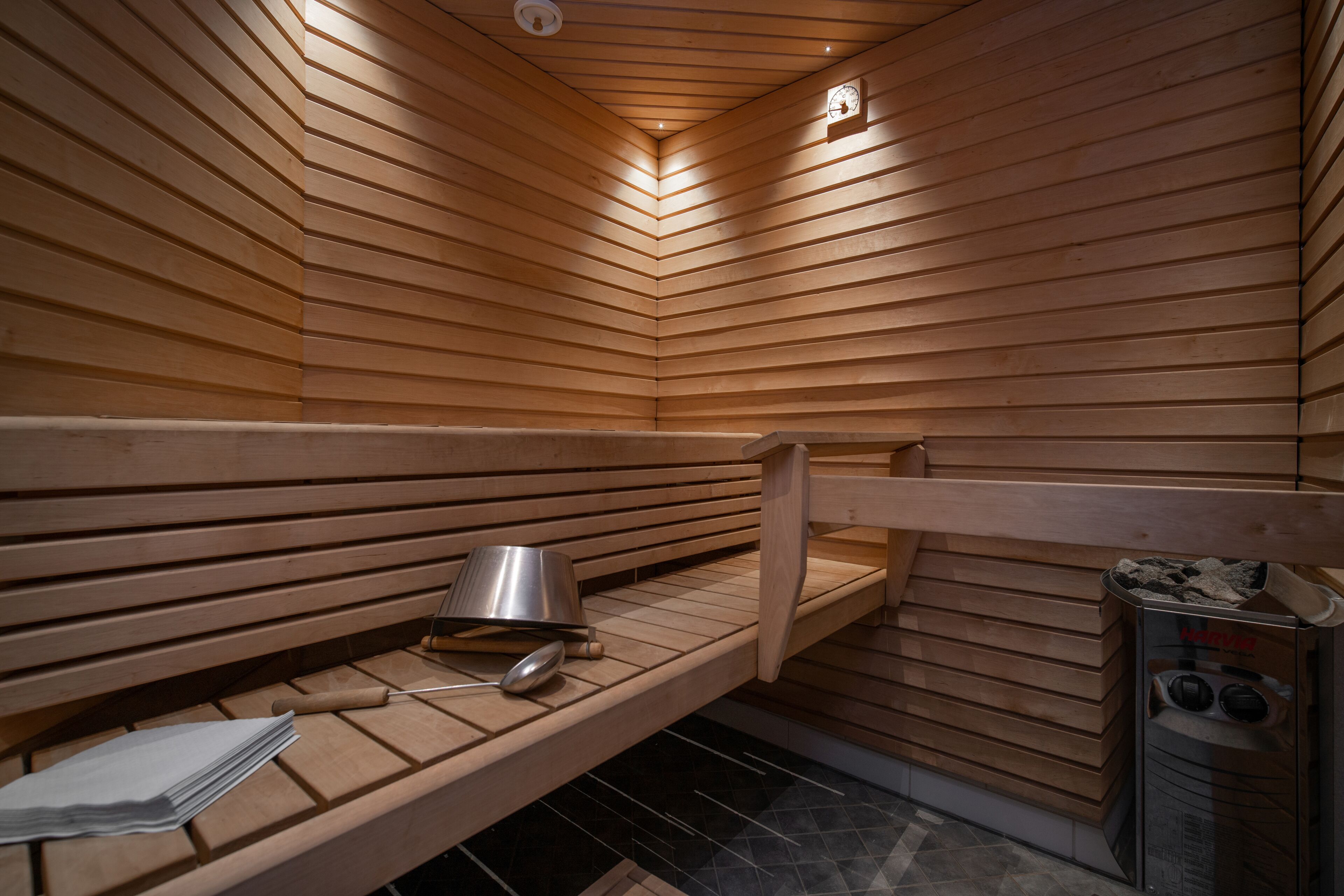 A sauna with wooden benches, a bench heater, and a sauna control panel.
