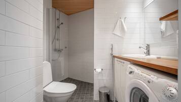 A modern bathroom with a toilet, shower, and washing machine.