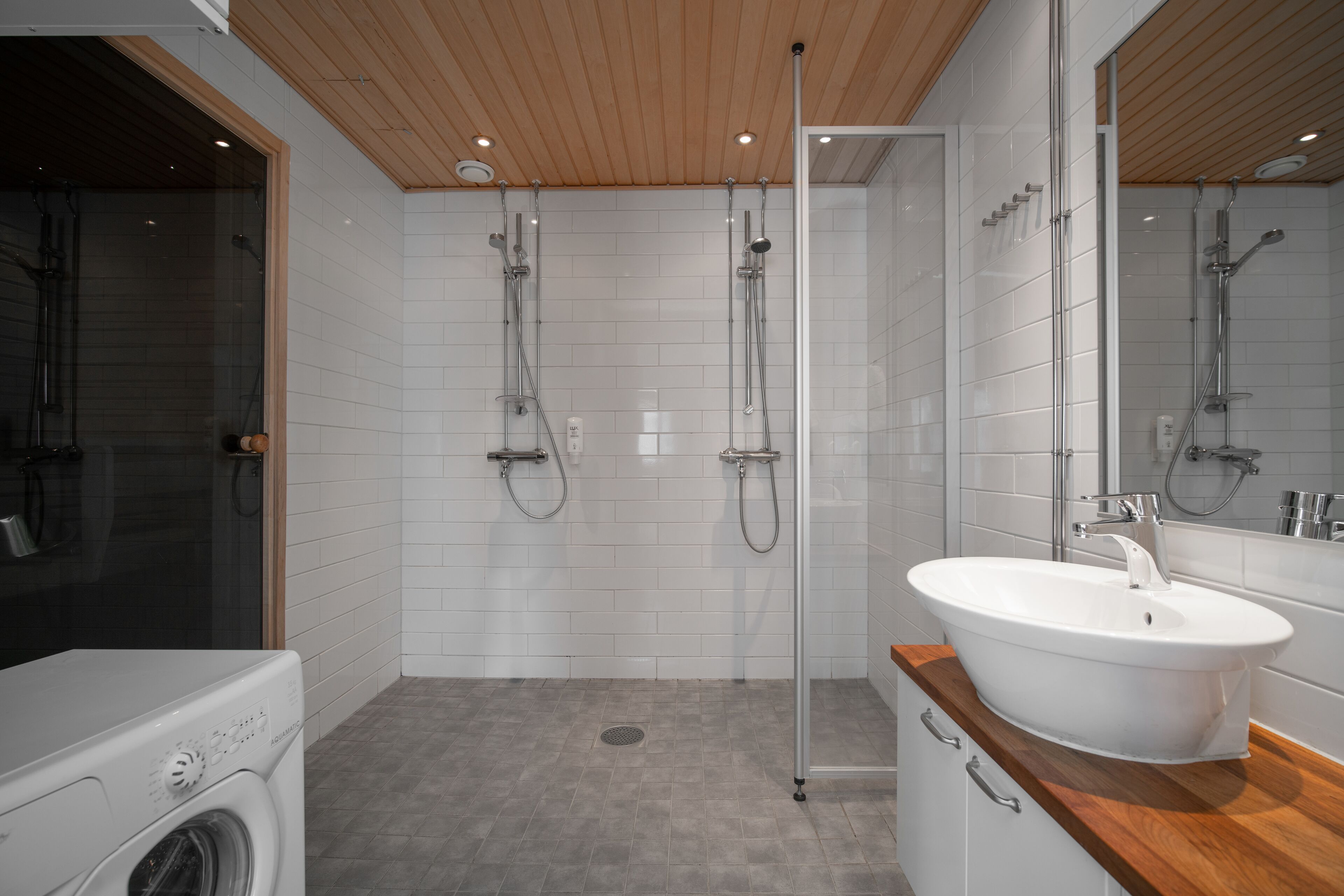 A modern bathroom with a glass shower enclosure, a built-in sink, and a washing machine.