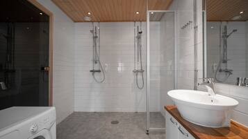 A modern bathroom with a glass shower enclosure, a built-in sink, and a washing machine.