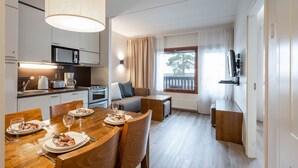 A modern kitchen with a dining area, a sofa, and a TV. - Ski-Inn RukaVillage (Kuusamo)