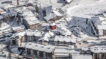 A snow-covered ski resort with multiple buildings, including a prominent red structure, and a winding ski slope.