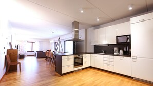 A modern kitchen with white cabinets, a black countertop, and a wooden floor. - Ski-Inn RukaVillage (Kuusamo)