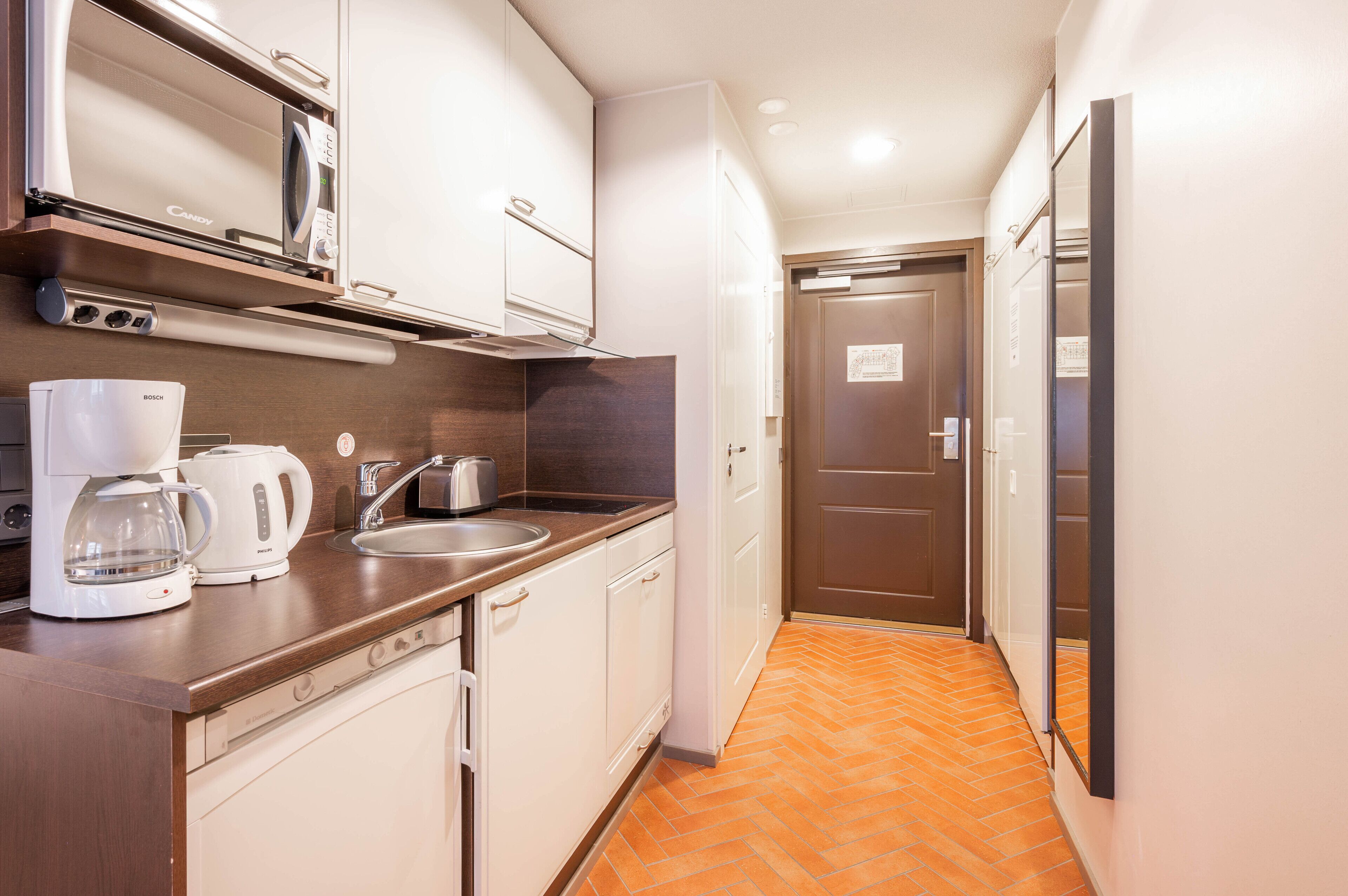 A compact kitchen with a Bosch coffee maker, a microwave, and a sink.