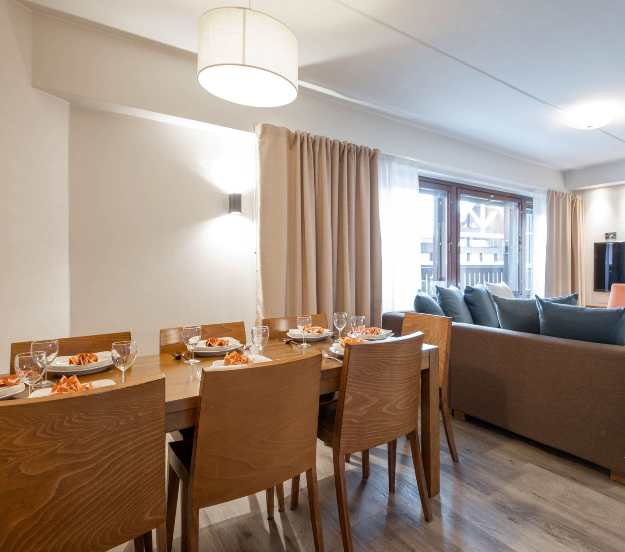 Una habitación de hotel moderna con comedor, sofá y televisor. Identificada como Ganadora de los Premios Mundiales de Esquí 2023.