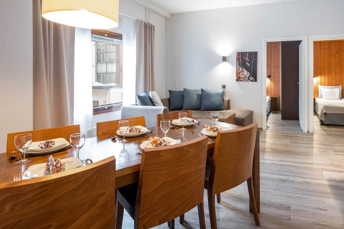 Une chambre d’hôtel comprenant un coin repas, un salon et un téléviseur fixé au mur.