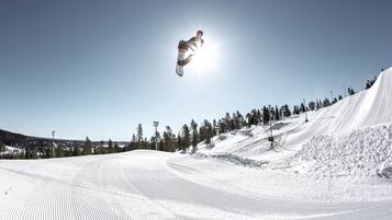 A snowboarder performing a jump on a snowy slope with a clear sky.