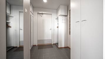 A hallway with white doors, a tiled floor, and a ceiling light.