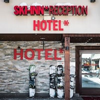 A hotel with a reception area and a sign that reads "SKI-INN RECEPTION HOTEL". Snowboards are displayed outside the entrance.
