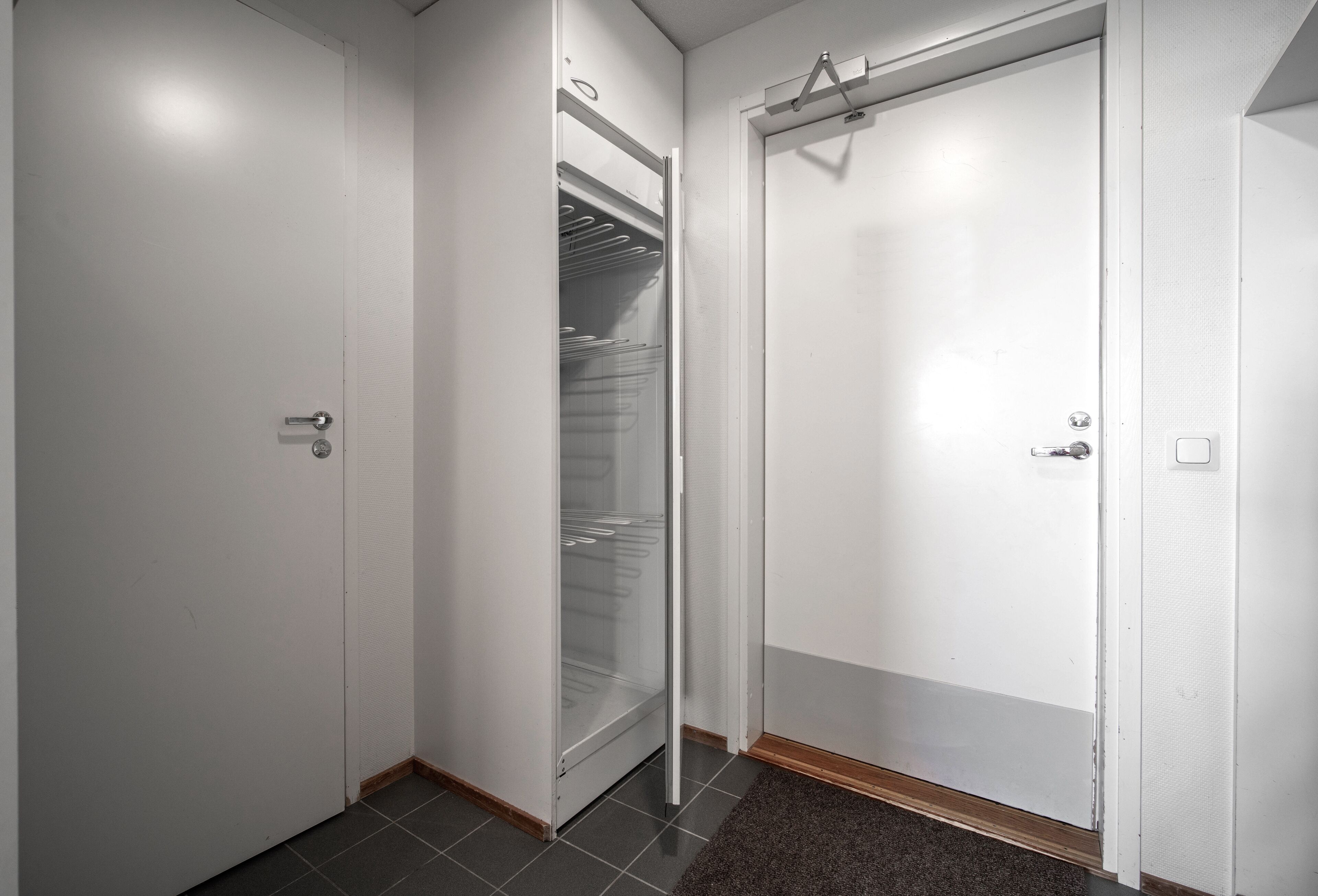 A hallway with three white doors, one with a glass panel, and a dark carpet.