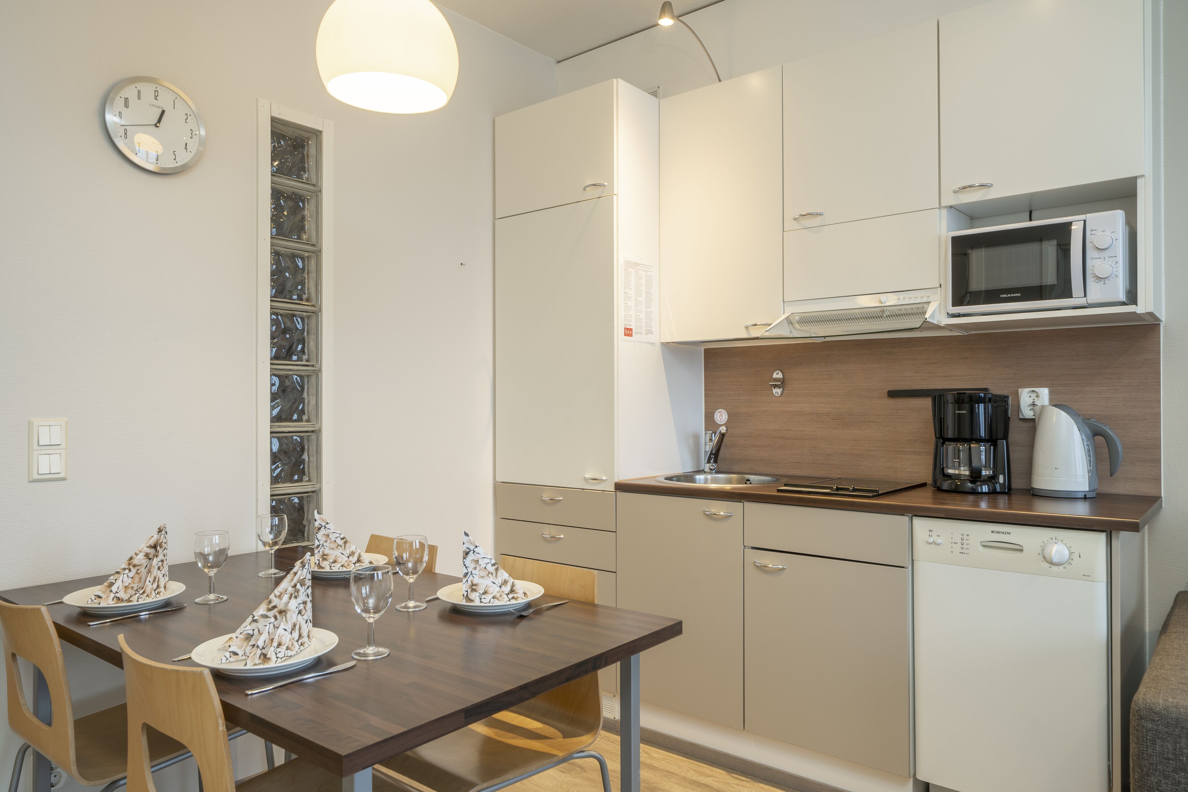 A modern kitchen with a wooden table set for dining, a microwave, and a dishwasher.
