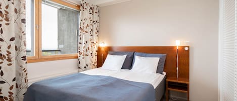 A neatly made bed with a blue bedspread, a wooden headboard, and two bedside lamps.