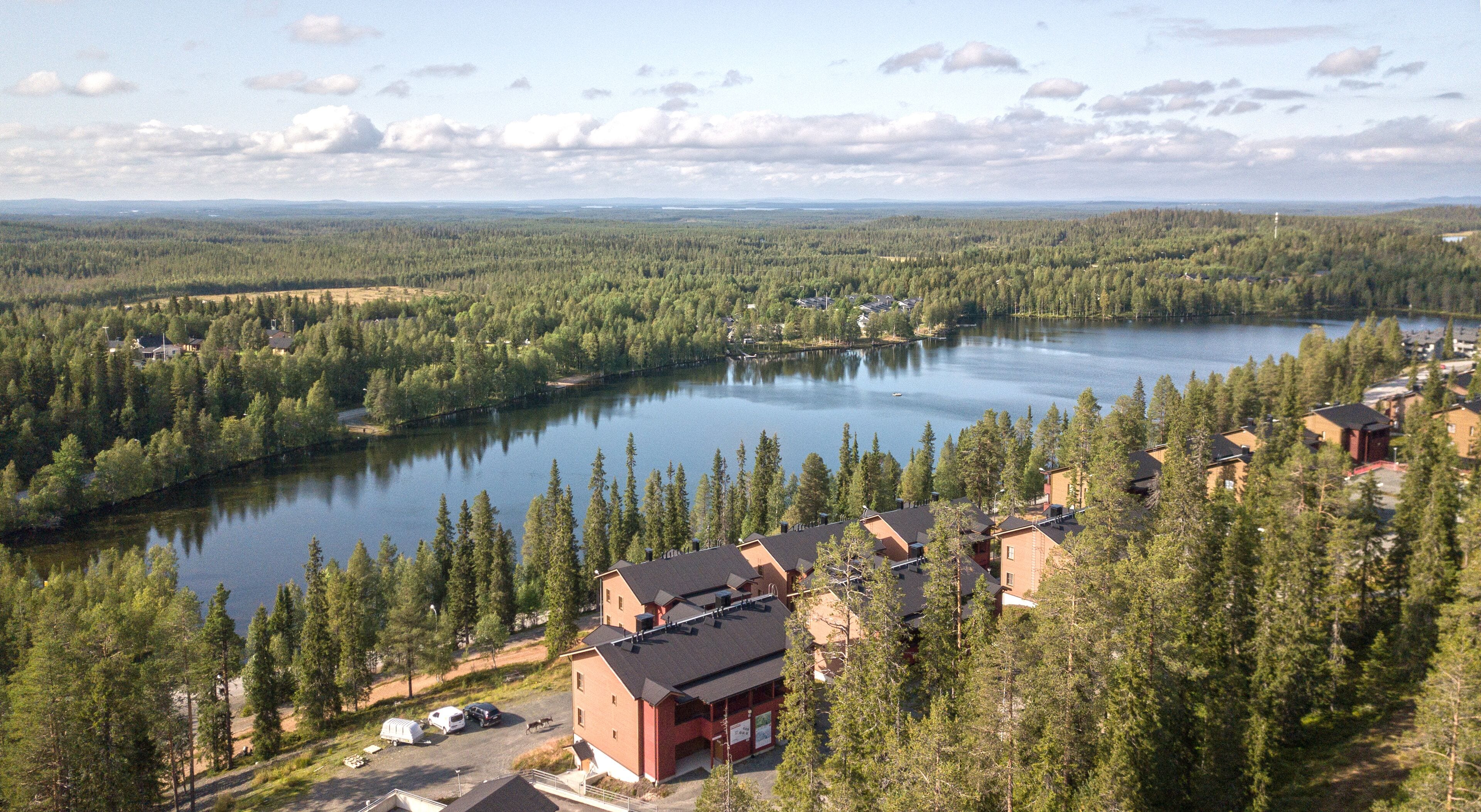 A lakeside property with multiple buildings, a dock, and a forested area.