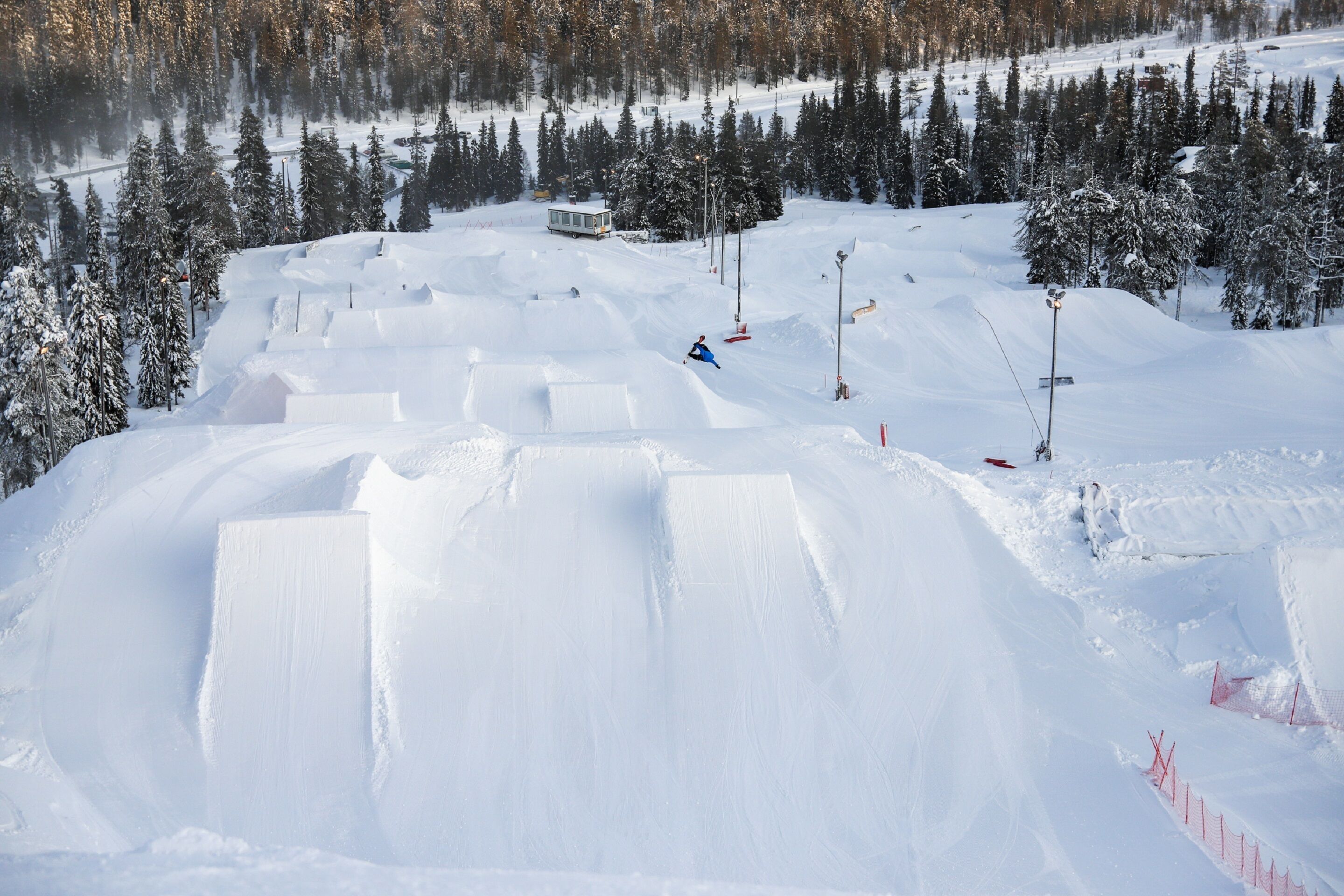 Une piste de ski enneigée, avec une personne qui descend une pente en skiant.