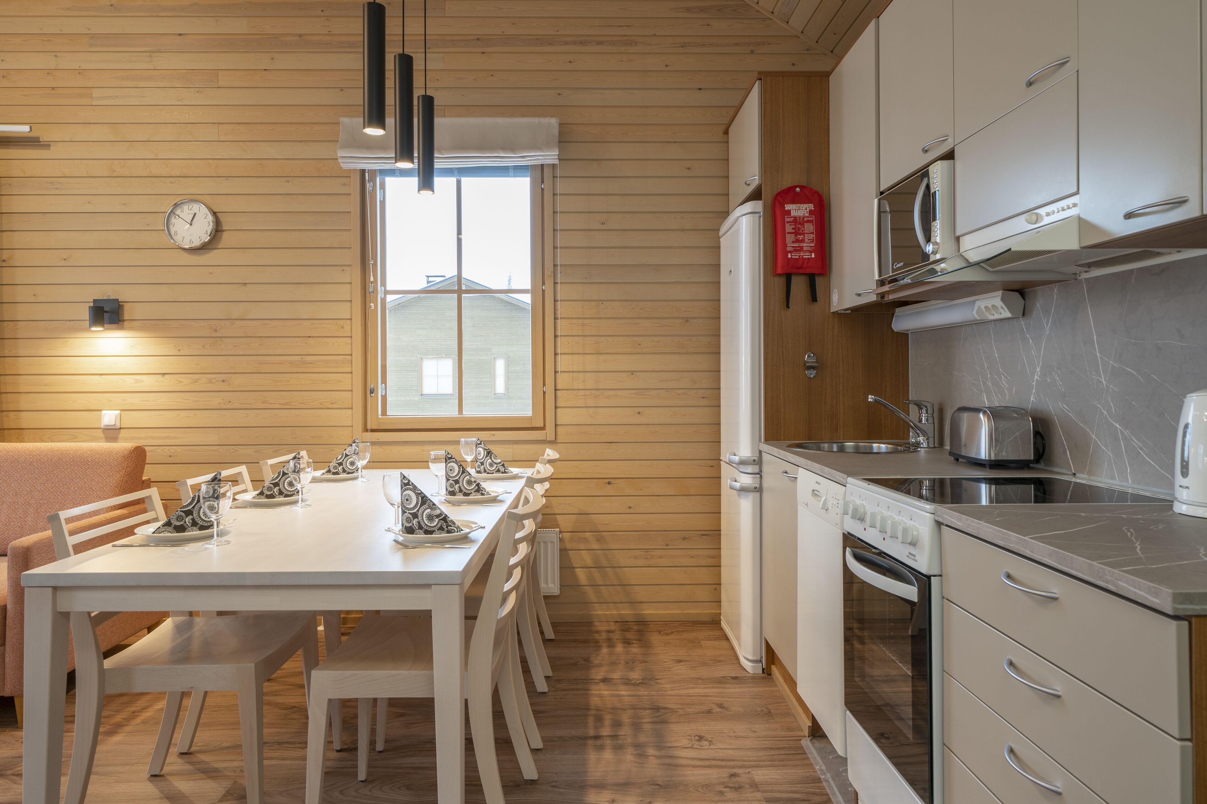 Une cuisine moderne avec des murs en bois, une table à manger avec des chaises, une horloge et une fenêtre.