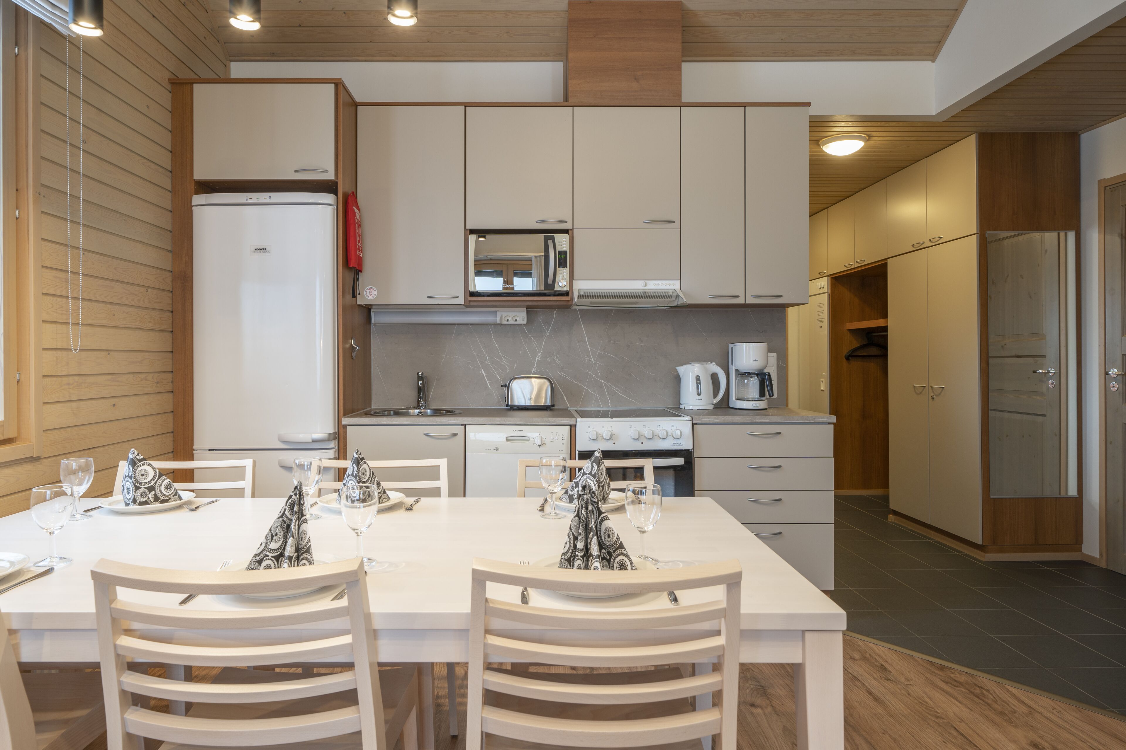 A modern kitchen with white cabinetry, a built-in microwave, and a stainless steel refrigerator.