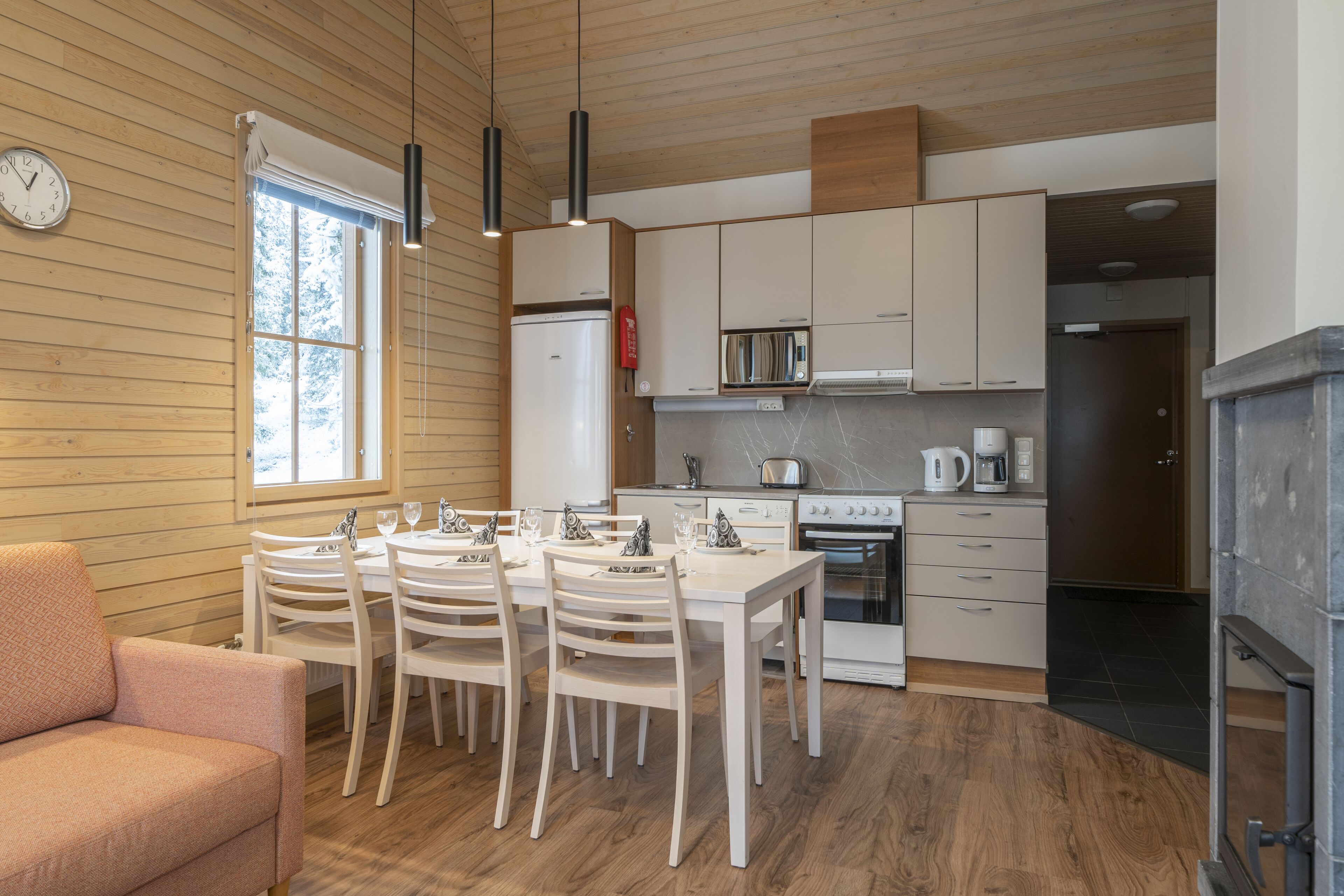 Una cocina moderna con paredes de madera, una mesa de comedor con sillas, un refrigerador, una estufa y un microondas.