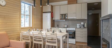 Una cocina moderna con paredes de madera, una mesa de comedor con sillas, un refrigerador, una estufa y un microondas.