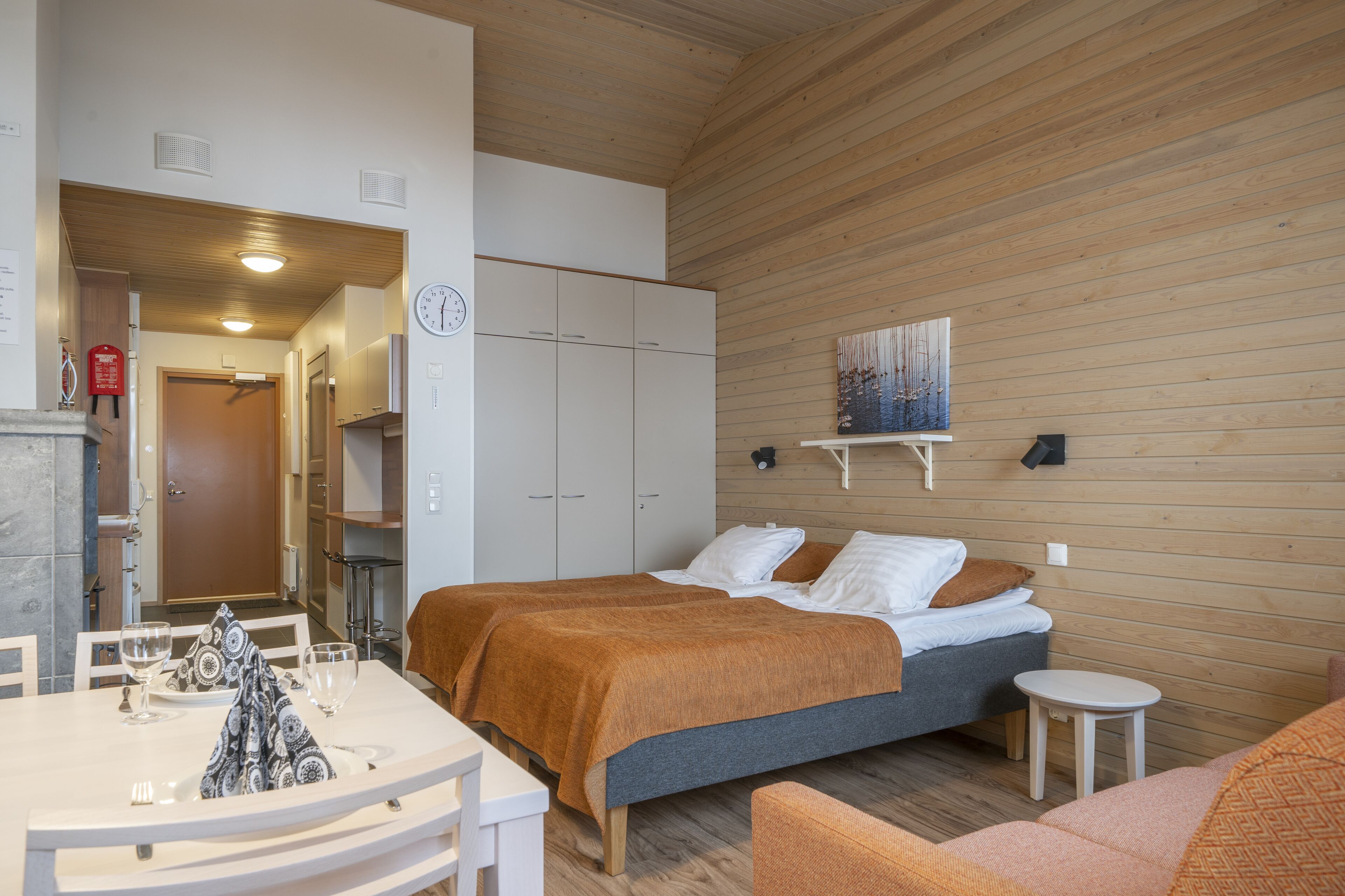 Una habitación de hotel moderna con dos camas, una zona de comedor y una pequeña cocina.
