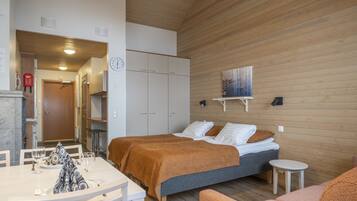 Una habitación de hotel moderna con dos camas, una zona de comedor y una pequeña cocina.