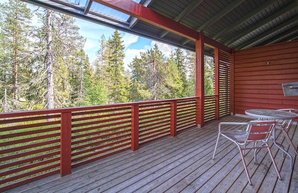 Una terraza de madera con barandillas rojas, una mesa y sillas.