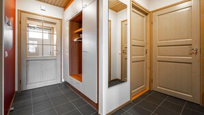 A hallway with a wooden ceiling, a white door with a window, a mirror, and a closed door. - Ski-Inn MastonAitio (Kuusamo)