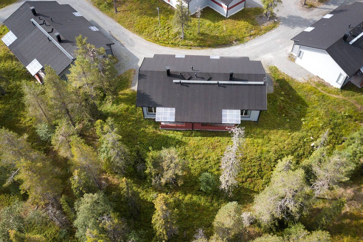 An aerial view of a residential area with multiple houses, surrounded by dense forest.