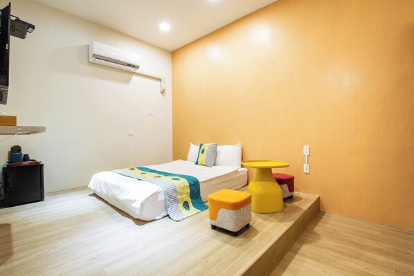 A hotel room with a bed, a small table, an air conditioning unit, and a wall-mounted outlet. - Clouds B&B (Liuqiu)