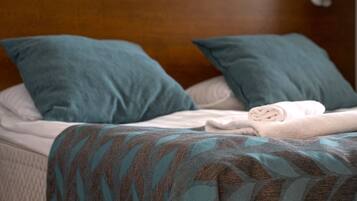 A neatly made bed with a patterned blanket, two pillows, and a folded towel.