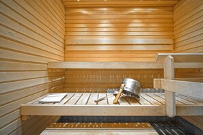 Una sauna con panche in legno e un catino di metallo.