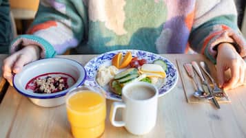 A breakfast setting with a plate of food, a bowl of cereal, a mug, and a glass of orange juice.