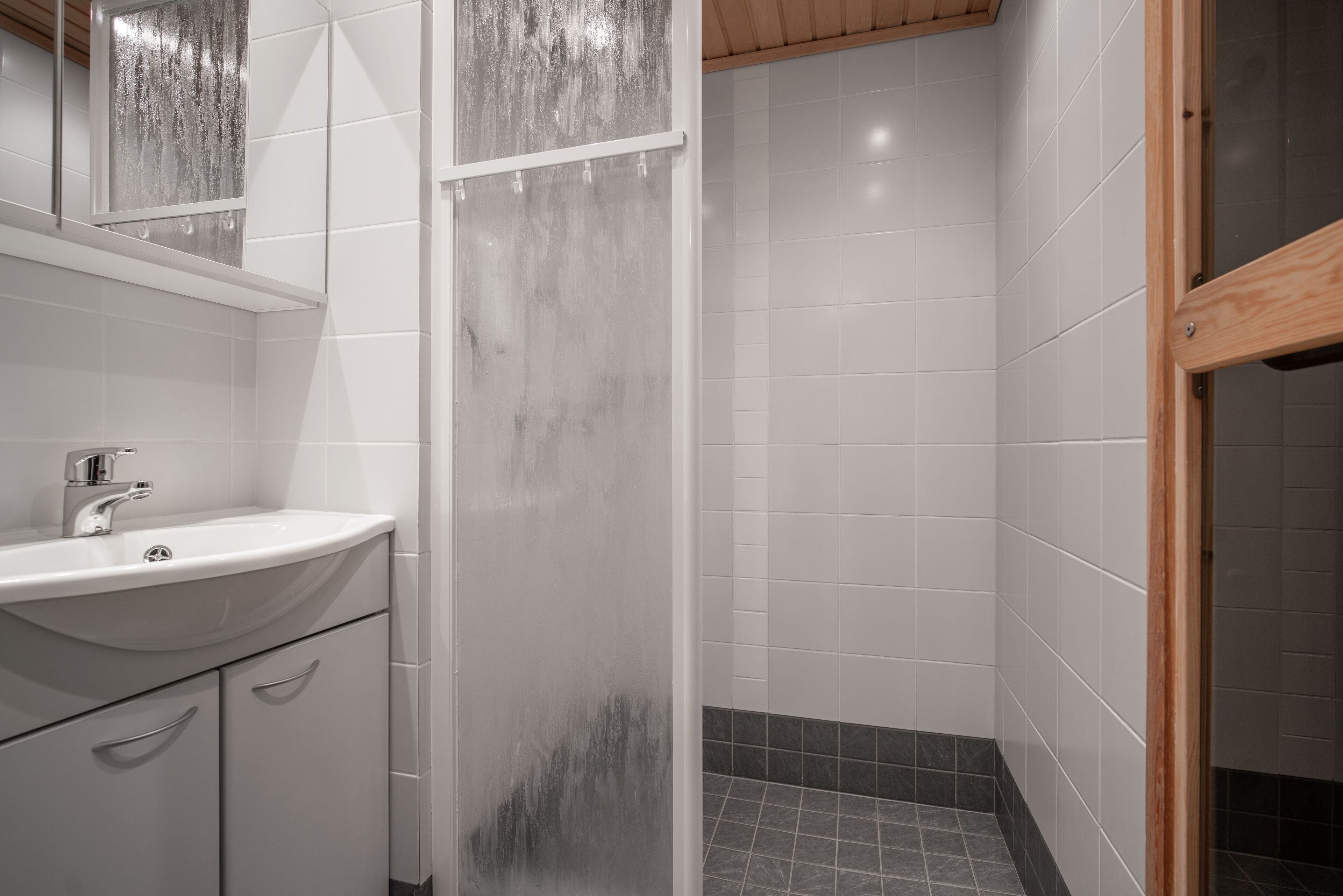 A bathroom with a white sink, mirror, and tiled walls.
