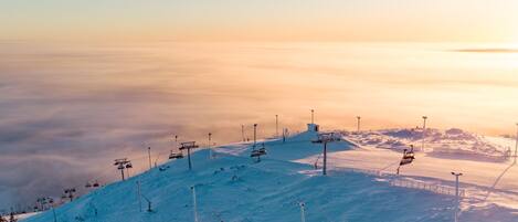A snow-covered ski slope with ski lifts and a clear sky.