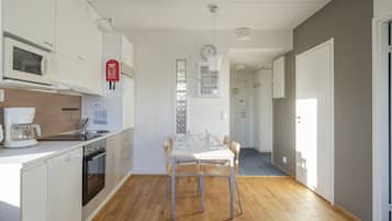 Une cuisine moderne avec des meubles blancs, un four à micro-ondes, une machine à café et une table à manger avec quatre chaises.