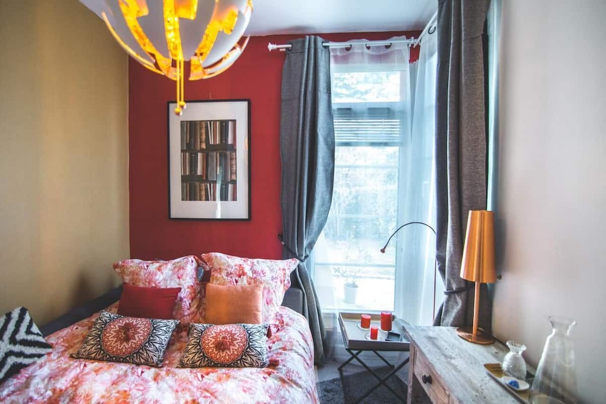 Une chambre à coucher avec un lit, un tableau encadré au mur, une fenêtre avec des rideaux et une table avec des bougies.