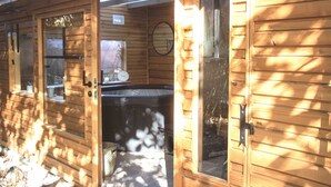A wooden cabin with a hot tub, a window, and a door. - Au Bien Venu (Noe)