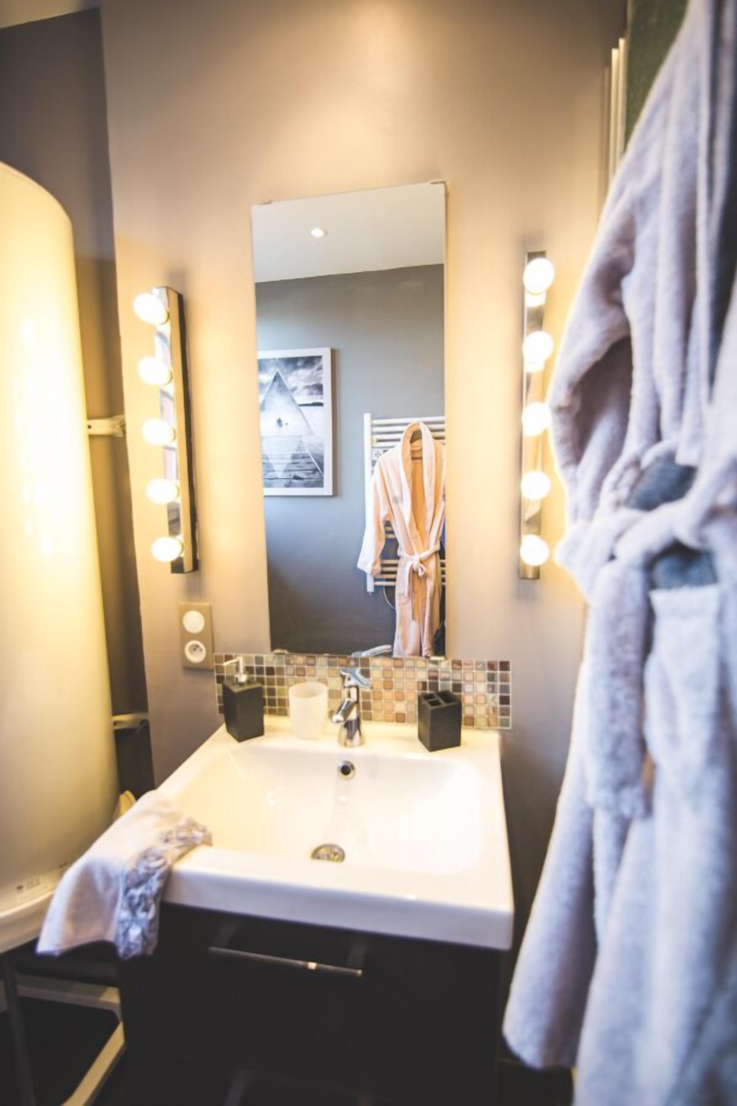 A bathroom with a sink, mirror, and lights.