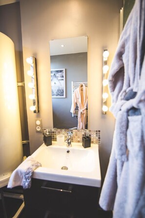 Un baño con lavabo, espejo e iluminación.