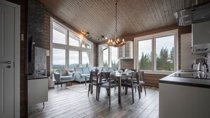 A spacious kitchen with a dining area, large windows, and a wooden ceiling. - Ski-Inn PyhäLinna (Pyhätunturi)