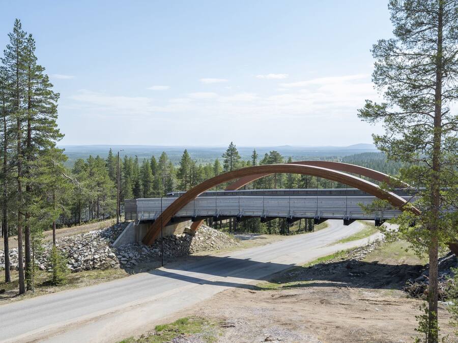 Un pont avec une arche incurvée enjambant une route, entouré d’arbres et sous un ciel dégagé.