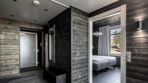 A modern interior with a wooden wall, a bench, a bed, and a view of the outdoors. - Ski-Inn PyhäLinna (Pyhätunturi)