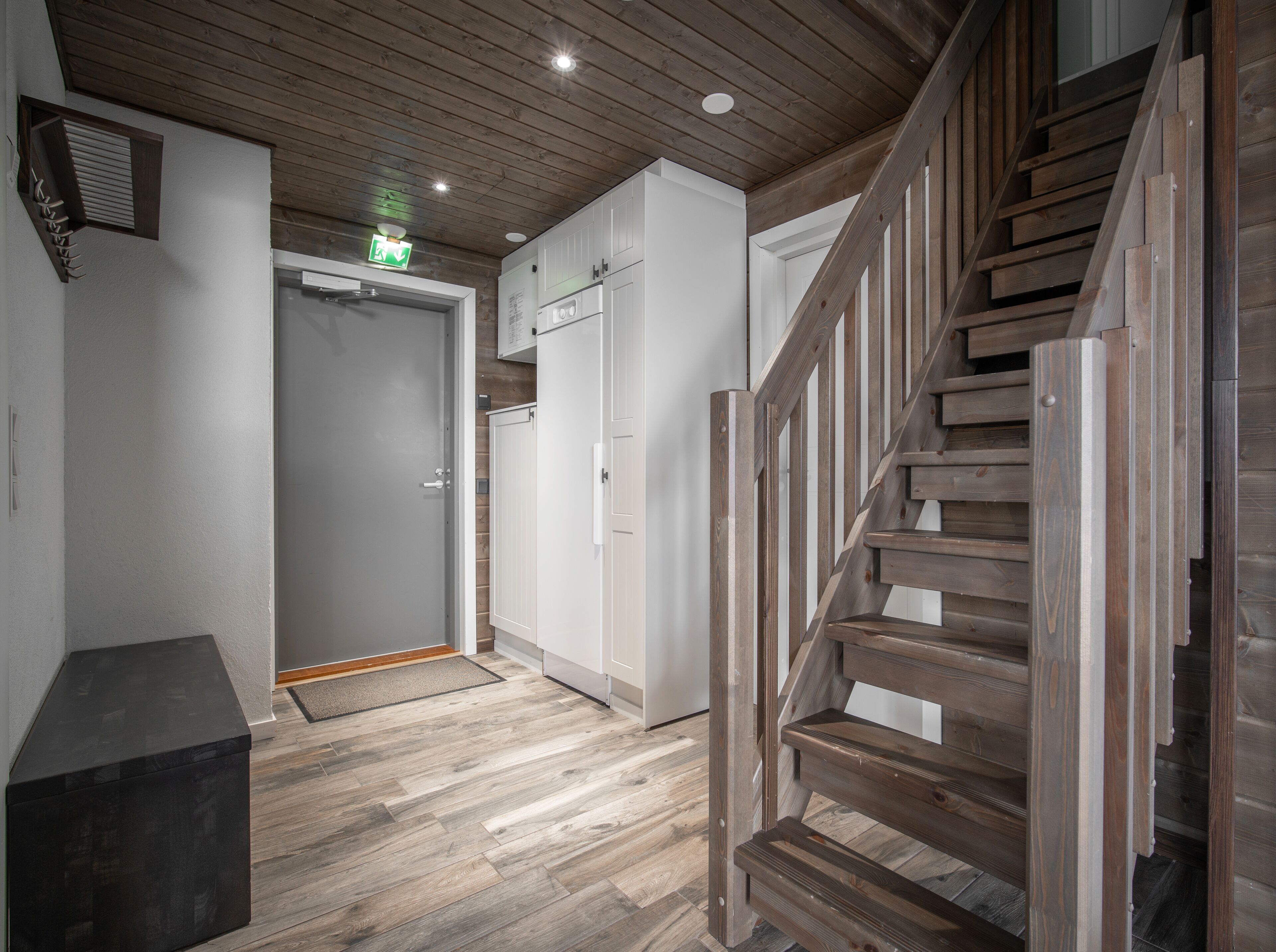 A wooden staircase leading to a landing with a white door and a small black box on the floor.