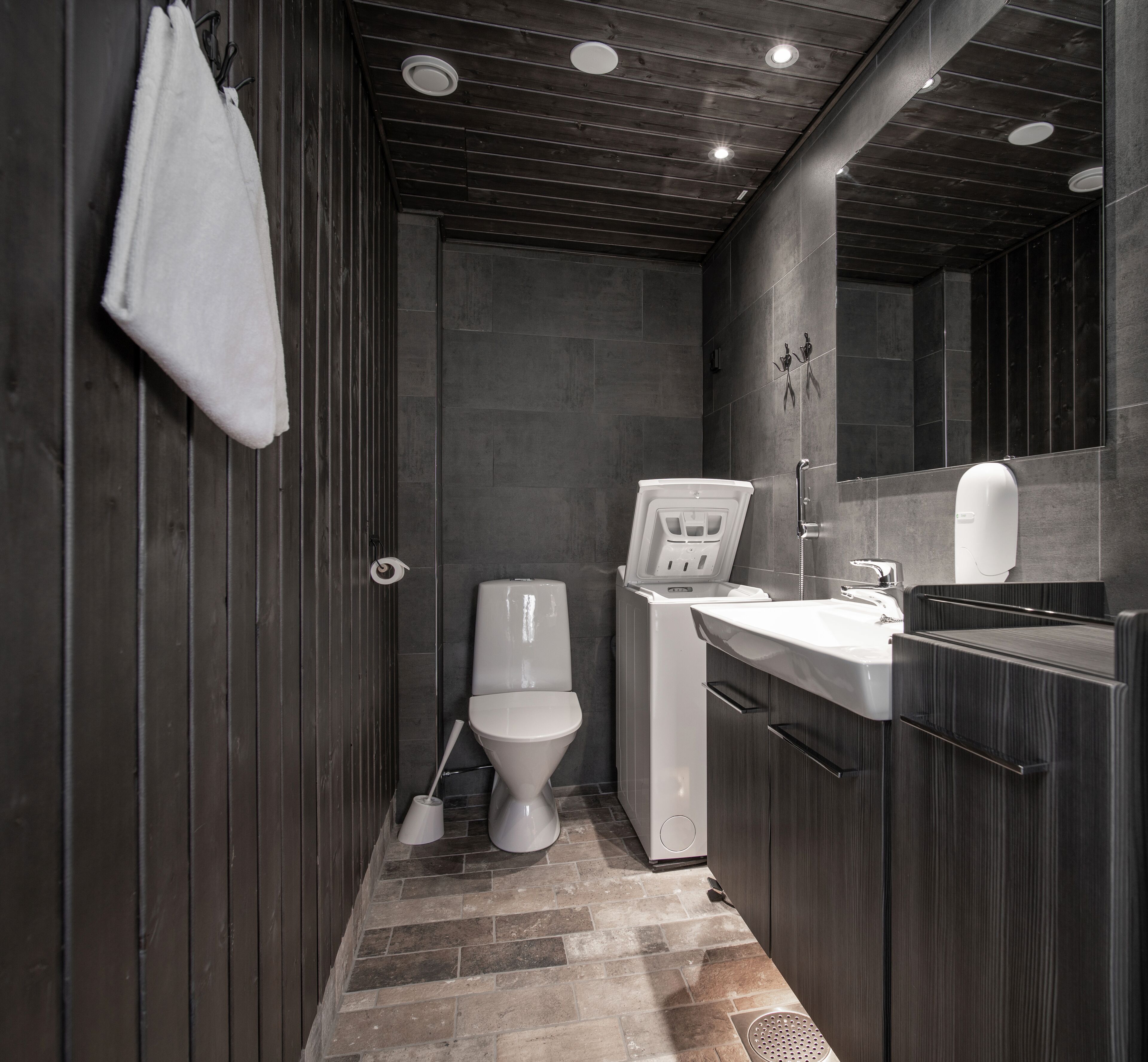 A compact bathroom with a toilet, sink, and mirror.
