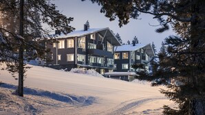 A modern multi-story house with large windows and a snow-covered landscape. - Ski-Inn PyhäLinna (Pyhätunturi)