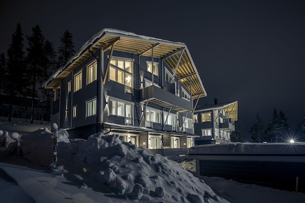A multi-story building with a sloped roof, large windows, and a balcony.