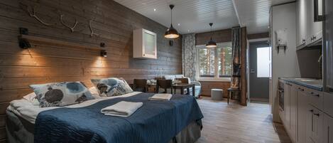 Un dormitorio moderno con pared de madera, una cama grande, un escritorio y una zona de cocina.