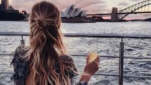 Una persona sentada en una terraza de madera con vista a un cuerpo de agua y un puente al fondo.