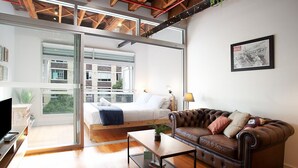 Una sala de estar moderna con una cama, un sofá de cuero, una mesa de centro y un televisor.