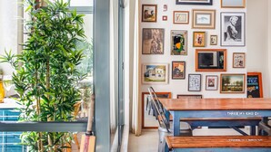 A dining area with a wooden table and chairs, a potted plant, and a wall adorned with various framed pictures. - ★ Funky Surry Hills Warehouse by ★ Sydney Dreams ★ (Darlinghurst)
