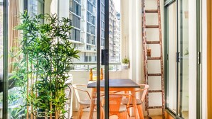 A balcony with a table and chairs, a potted plant, and a ladder. - ★ Funky Surry Hills Warehouse by ★ Sydney Dreams ★ (Darlinghurst)